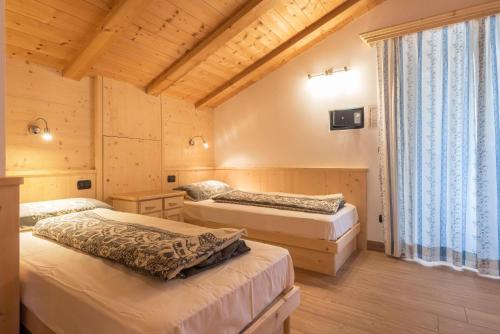1 dormitorio con 2 camas y ventana grande en Villa Doris en Canazei