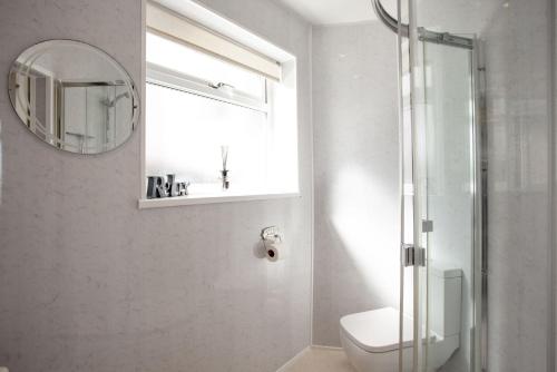 a bathroom with a toilet and a window and a mirror at Cliff Cottage, Brixham in Brixham