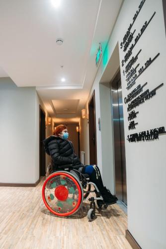 a woman sitting in a wheelchair in a room at Boutique Hotel Kviria in Tʼelavi