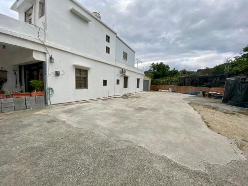 an empty parking lot in front of a white building at 居家民宿-岩手二館 in Eluan