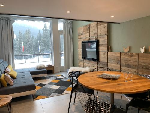 - un salon avec une table, un canapé et une télévision dans l'établissement Flaine Forum L1 Cassiopée Mezzanine & Terrasse, à Flaine
