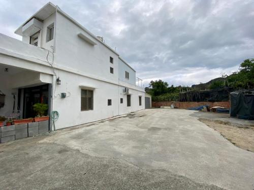 a white building with a parking lot next to it at 居家民宿-岩手二館 in Eluan