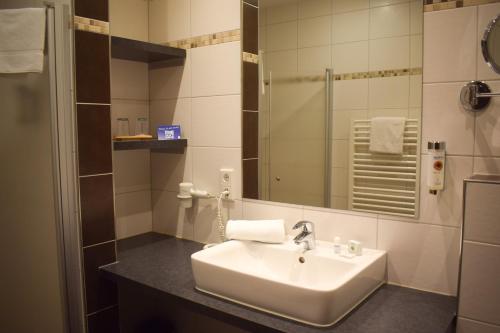 a bathroom with a sink and a mirror at Akzent Hotel Jonathan in Lippstadt
