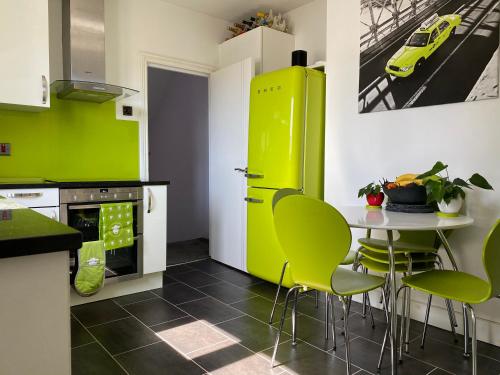 a kitchen with green cabinets and a table with green chairs at 3 bed Apartment in Colliers Wood in London