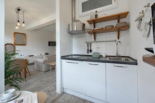 una cucina con armadi bianchi e lavandino di Via Avelli, 4 - Florence Charming Apartments - Delightful and bright 3rd-floor apartment without elevator, overlooking one of Florence's most beautiful squares, Exceptionally located for exploring the city a Firenze