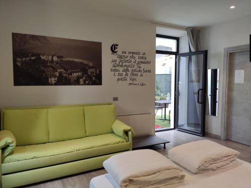 ein Wohnzimmer mit einem grünen Sofa und einem Tisch in der Unterkunft Antica Campione Rooms & Hostel in Campione del Garda