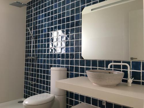 Un baño con azulejos azules, lavabo e inodoro. en Aiguaneu Luxury Nàutic, en Blanes
