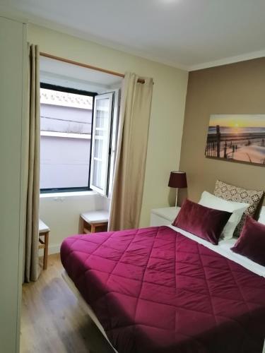 ein Schlafzimmer mit einem großen lila Bett und einem Fenster in der Unterkunft Aliciamar E by Casas de Setúbal in Setúbal