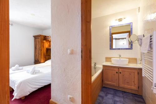 a bathroom with a bed and a sink and a mirror at Chalet des Neiges Plein Sud in Val Thorens