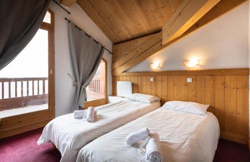 two beds in a room with a window at Chalet des Neiges Plein Sud in Val Thorens