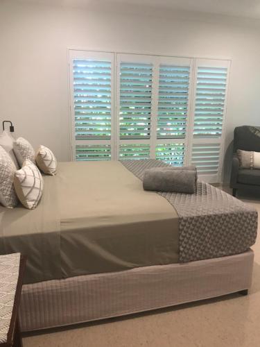 a large bed in a bedroom with windows at Chez Brolga in Port Douglas