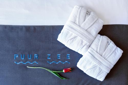 une paire de gants blancs et une fleur sur une couverture dans l'établissement Boutique hotel Puur Zee - Adults Only, à Wijk aan Zee