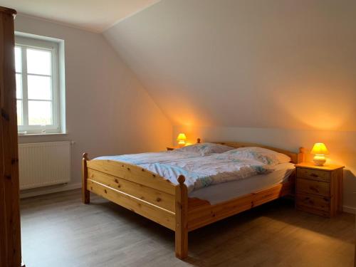 a bedroom with a wooden bed with two lamps on it at Ferienvermietung Familie Jensen in Tetenbüll