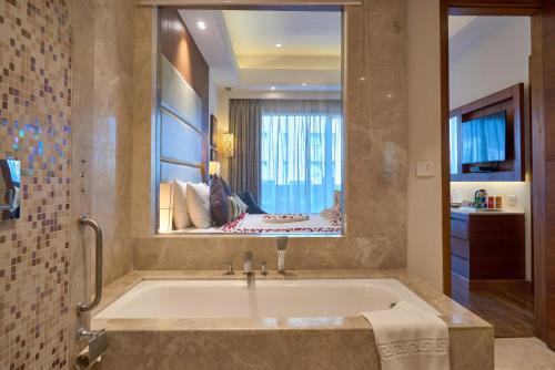 a bath tub in a bathroom with a large mirror at The P L Palace Agra in Agra