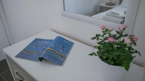 ein Buch und eine Vase Blumen auf einem weißen Tisch in der Unterkunft Luminosa - Cala Gonone in Cala Gonone