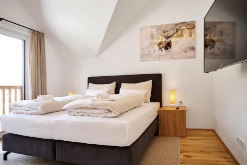 a bedroom with a large bed with white sheets at die Tauplitz Lodges - Alm Lodge A13 by AA Holiday Homes in Tauplitz