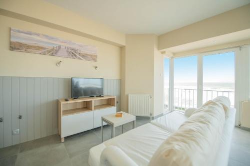 a living room with a white couch and a television at vakantie Appartement Bel 'Vu in Middelkerke