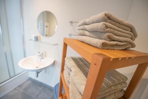 a stack of towels on a wooden shelf in a bathroom at vakantie Appartement Bel 'Vu in Middelkerke