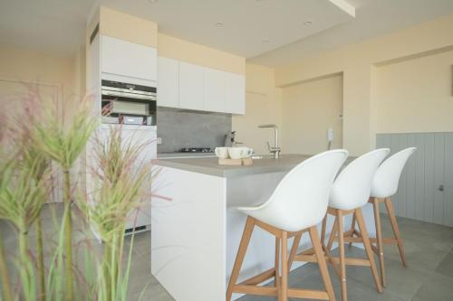 a kitchen with white chairs and a kitchen island at vakantie Appartement Bel 'Vu in Middelkerke