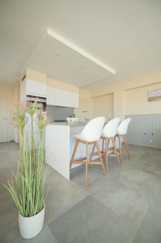 a kitchen with white chairs and potted plants at vakantie Appartement Bel 'Vu in Middelkerke