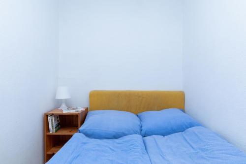 a bed with blue sheets in a bedroom with a night stand at Bungalows Nadmorska 106 in Sarbinowo
