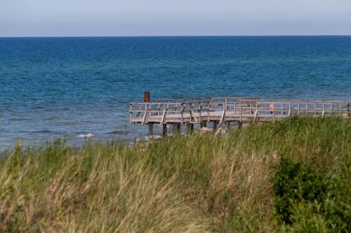 a wooden pier on the beach next to the ocean at Bungalows Nadmorska 106 in Sarbinowo