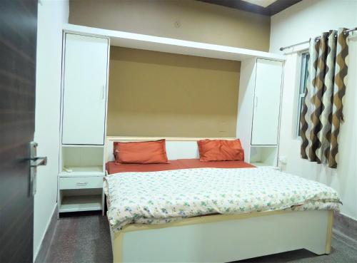 a small bedroom with a bed with orange pillows at Hotel Siddharth in Tanakpur