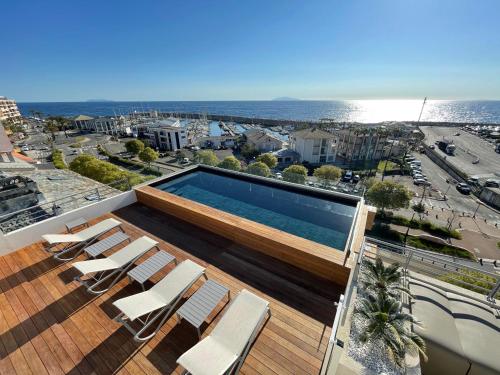 a swimming pool on the roof of a building with chairs at Hotel Port Toga in Bastia