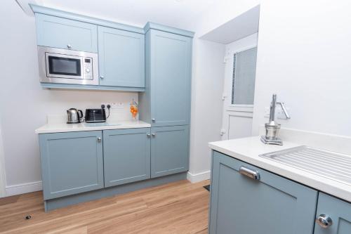a kitchen with blue cabinets and a sink at Stable Court Apartments in Antrim