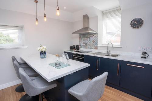 a kitchen with blue cabinets and a table with chairs at Stable Court Apartments in Antrim