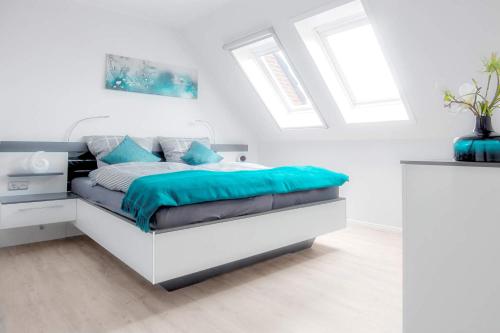 a white bedroom with a bed with blue pillows at Seewind in Heiligenhafen
