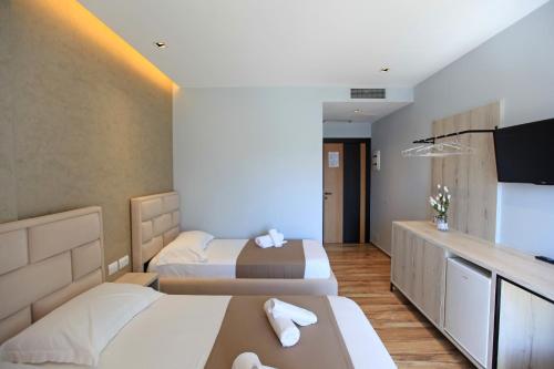 a hotel room with two beds and a flat screen tv at Hotel Citrus in Ksamil