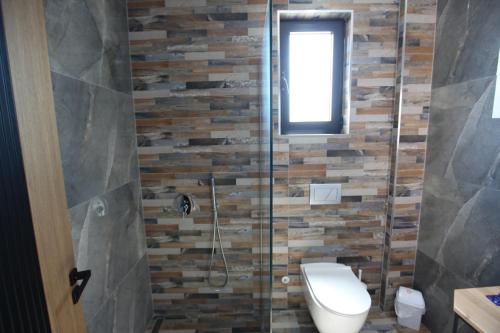 a bathroom with a toilet and a glass shower at Hotel Citrus in Ksamil