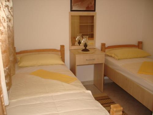 two beds in a room with a nightstand and a bed sidx sidx at Apartments Medin Danilo in Petrovac na Moru