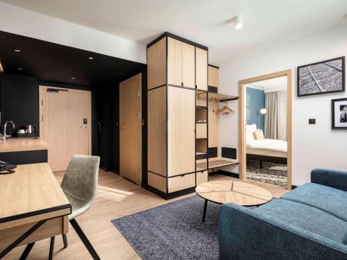a living room with a blue couch and a table at Mercure Warszawa Ursus Station in Warsaw