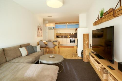 a living room with a couch and a large television at die Tauplitz Lodges - Wasserfall Lodge C2 by AA Holiday Homes in Tauplitz