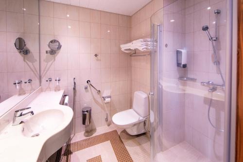 a bathroom with a toilet and a sink and a shower at Santa's Resort & Spa Hotel Sani in Kalajoki