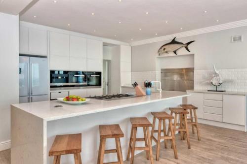 a kitchen with a large island with wooden stools at Marlin Manor in Struisbaai