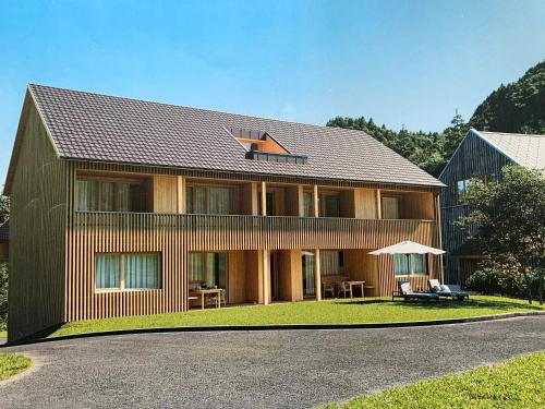 une grande maison avec un toit en gambrel dans l'établissement Wasserfall Apartments Mellau, à Mellau