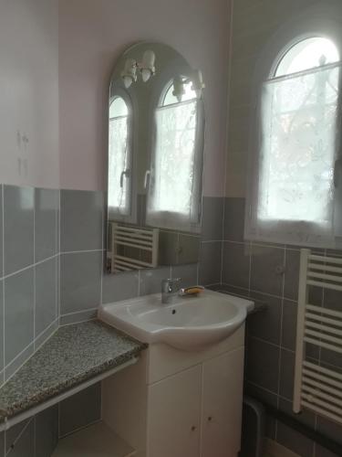 une salle de bain blanche avec un lavabo et deux fenêtres dans l'établissement GITE JARDIN/TERRASSE COSY PRES PLAGES, à Arès