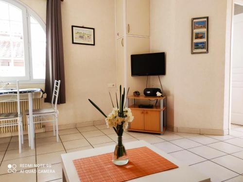 a living room with a vase of flowers on a table at GITE JARDIN/TERRASSE COSY PRES PLAGES in Arès