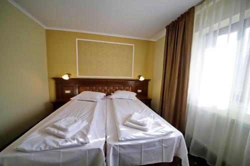 a bedroom with two beds with white sheets and a window at Montebello in Predeal