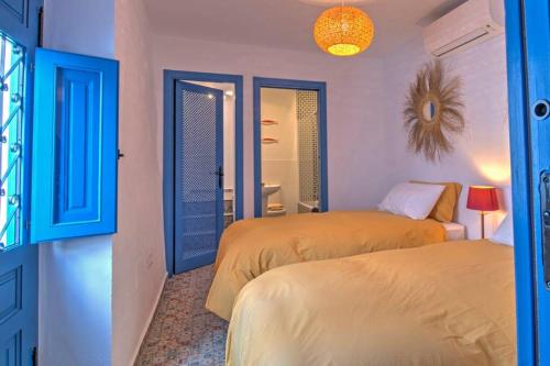 a bedroom with two beds and a blue door at Casa Beaumont - awesome Andalusian townhouse in Cómpeta