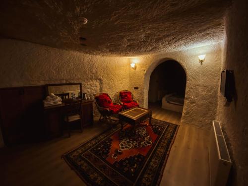 a room with two red chairs and a table in a cave at Asteria Cave Hotel in Göreme
