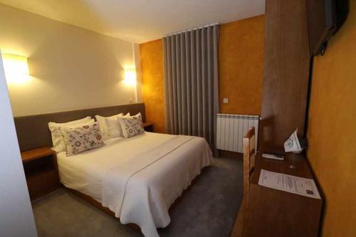 a hotel room with a large bed and a desk at Quinta dos Avidagos AgroTurismo Mirandela in Mirandela