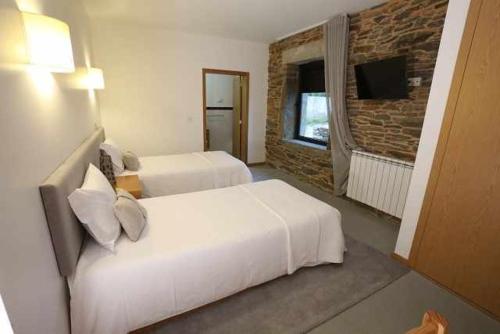 a hotel room with two beds and a television at Quinta dos Avidagos AgroTurismo Mirandela in Mirandela