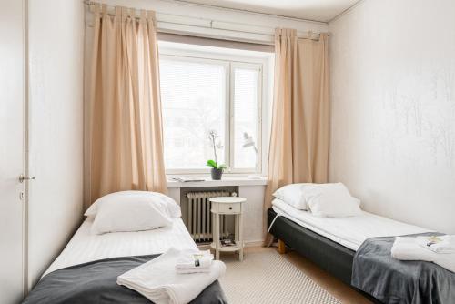 twee bedden in een kleine kamer met een raam bij Apartments Borg in Pori