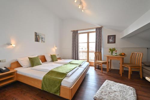 ein Schlafzimmer mit einem großen Bett, einem Tisch und Stühlen in der Unterkunft Gasthaus - Hotel Alt Fürstätt in Rosenheim