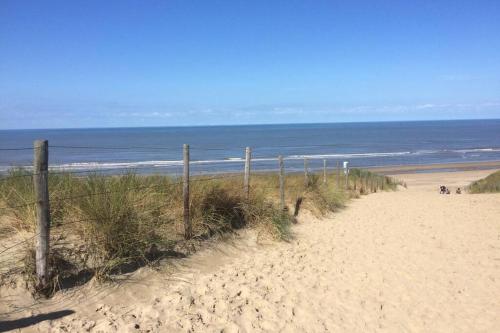 a sandy beach with a fence and the ocean at Beachhouse SeaBreeze - vernieuwd! in Noordwijk