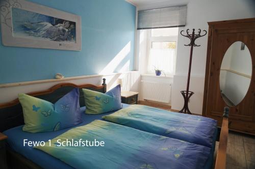 Schlafzimmer mit einem Bett mit blauer Bettwäsche und einem Spiegel in der Unterkunft Ferienwohnung Füssel in Rathmannsdorf